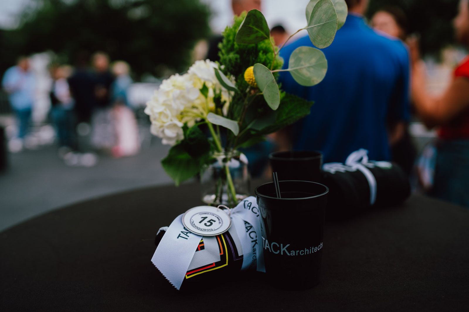 Table detail with flowers, a TACK architects cup, and a 15th anniversary gift tag